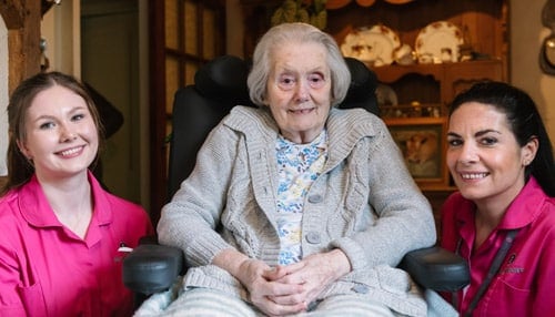 Two female Carers sitting beside female client in wheelchair